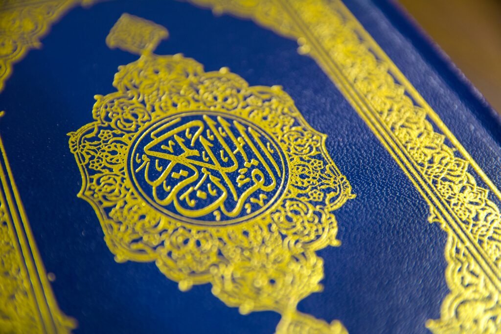 pexels-photo-3360048-3360048 Close-up of intricate gold Quranic calligraphy on a blue cover, showcasing elegant Islamic design.