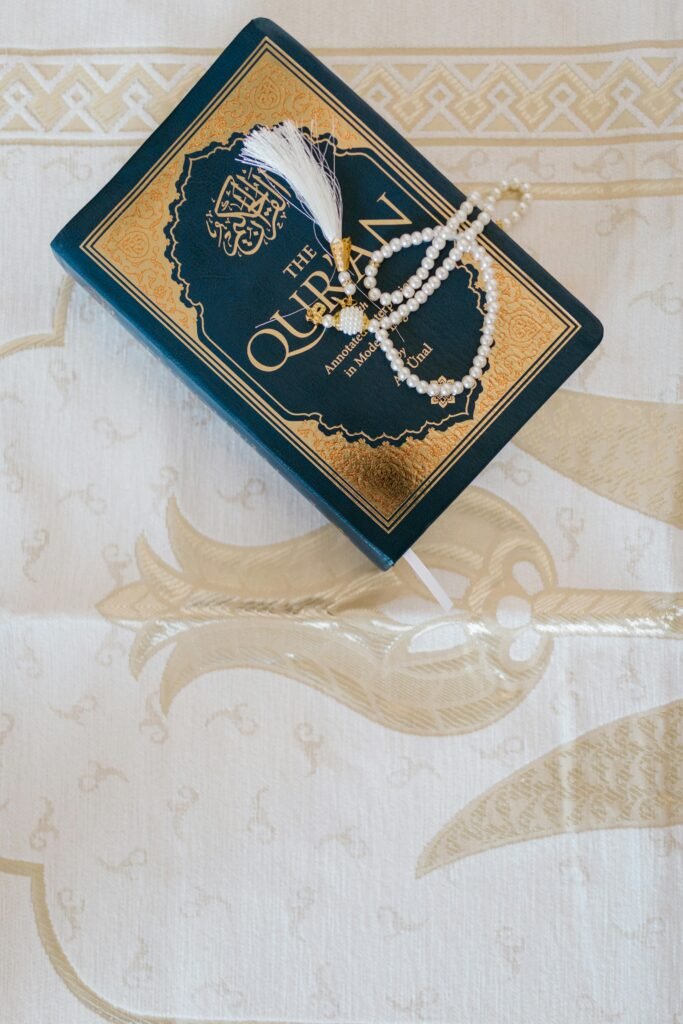 pexels-photo-7249294-7249294 Top view of an elegant Quran and prayer beads on ornate white cloth, symbolizing Islamic faith.